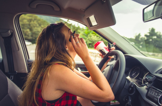 A woman applies makeup while driving - car insurance in Georgia