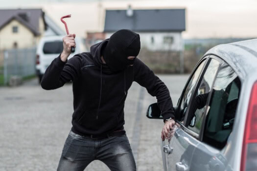 A thief breaks into a car to steal it - cheap car insurance in Georgia.