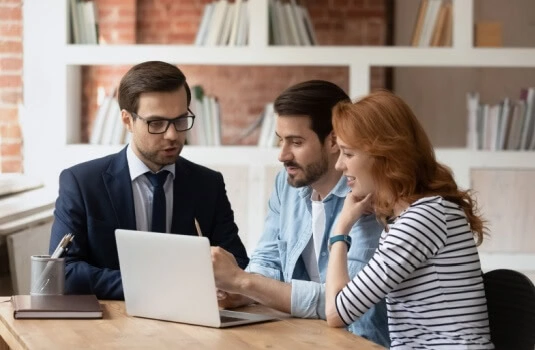 Insurance agent explaining potential discounts on renters insurance to a couple as they smile. 