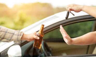 Man holding a beer in one hand and refusing to hand over car keys to a drunk driver - Southern Harvest Cheap auto insurance in Georgia.