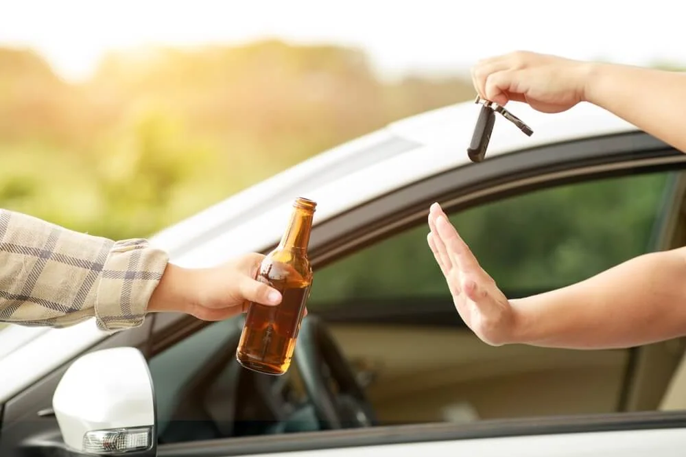 Man holding a beer in one hand and refusing to hand over car keys to a drunk driver - Southern Harvest Cheap auto insurance in Georgia.