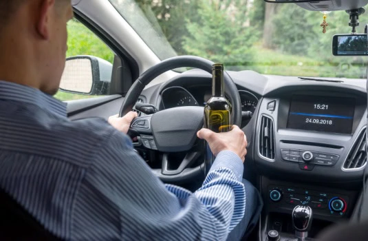 Man sitting inside his car with a beer in his hand
