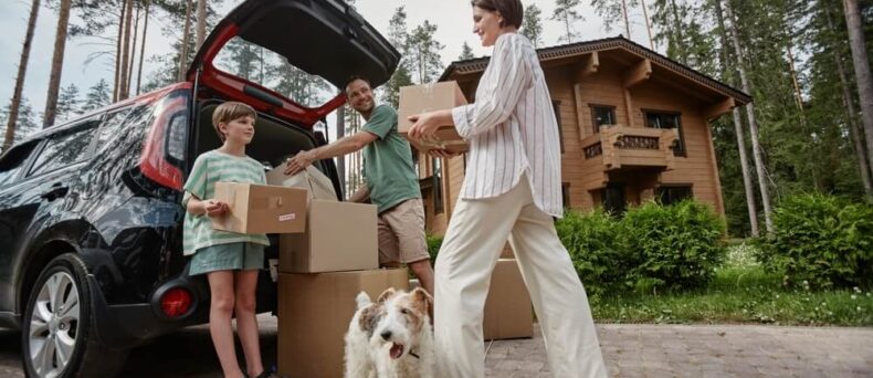 Full length portrait of happy family unloading boxes from car trunk while moving into new house with pet dog - Southern Harvest Cheap homeowners in Georgia.