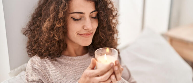 Woman smelling a scented candle in her home - Southern Harvest Cheap homeowners in Georgia.